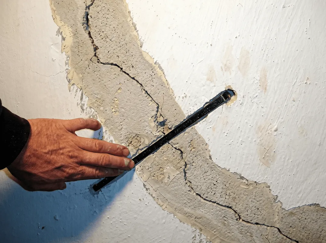 A wall with a large crack is being inspected by a professional in Myrtle Beach, SC